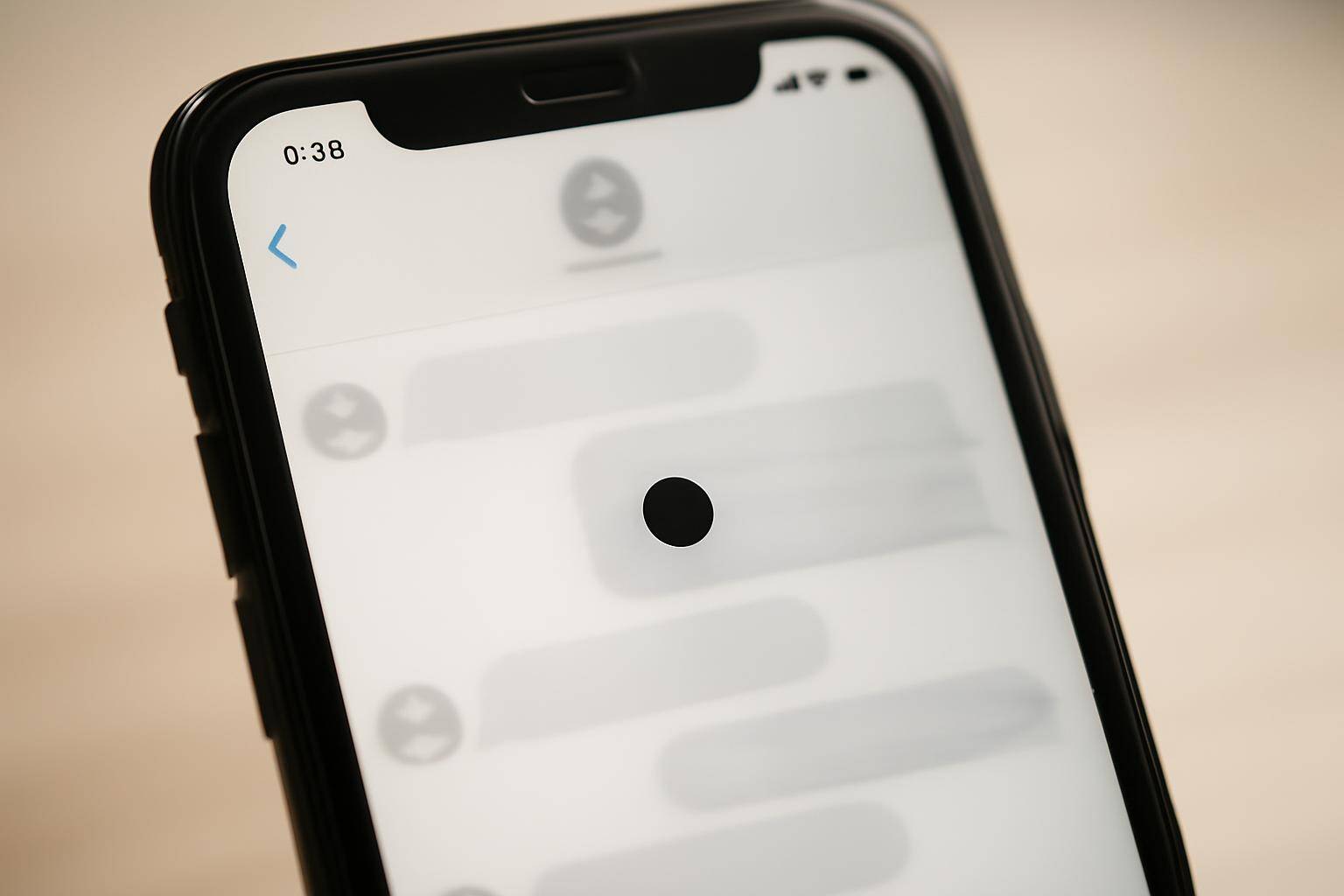 A black dot glyph glitching on an iPhone Messages screen with a frozen chat bubble